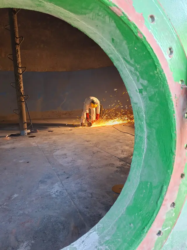 Trabajador esmerilando al interior de un estanque